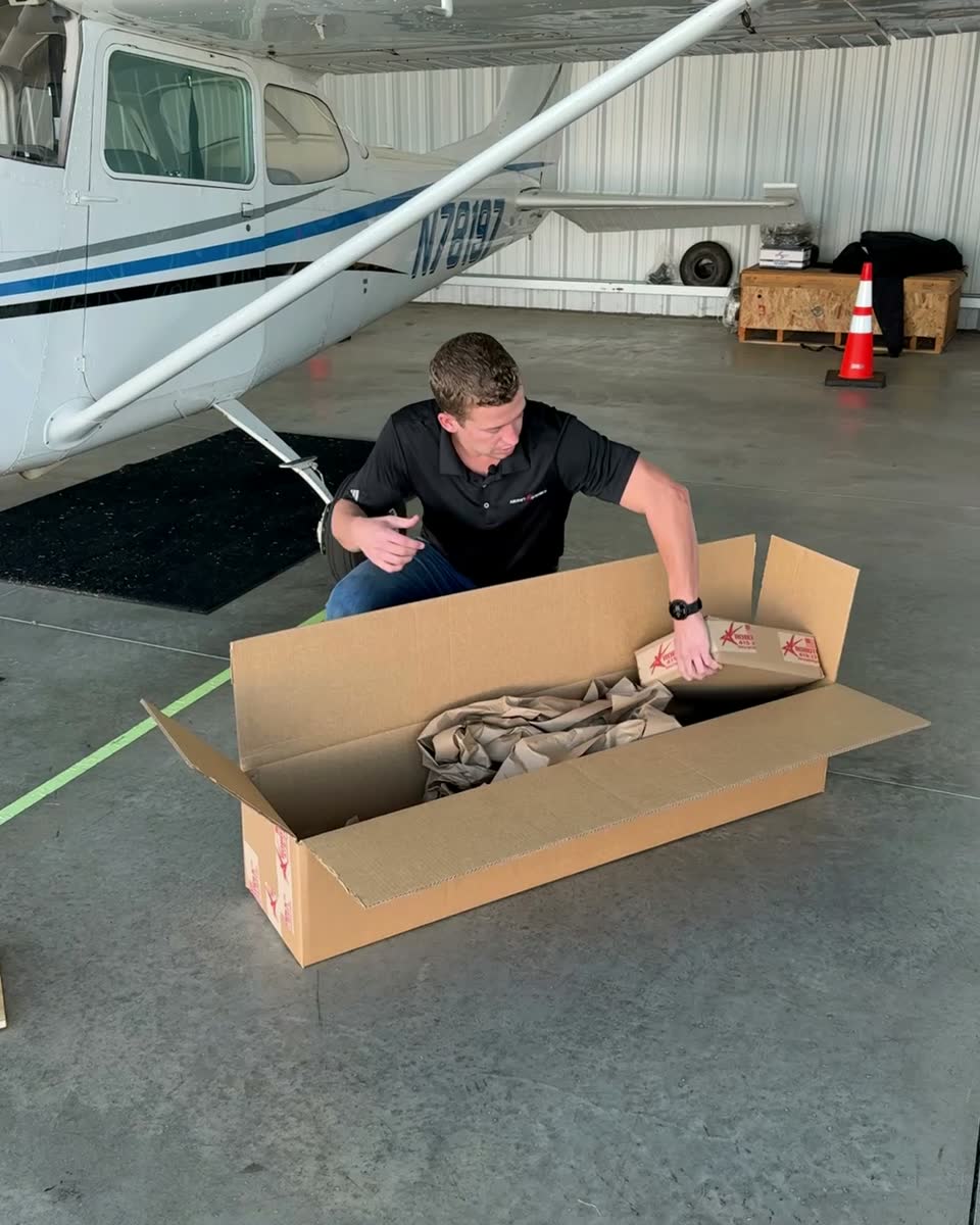 A Robotow kit box open on a hangar floor beside a Cessna, a smaller labeled box coming out.