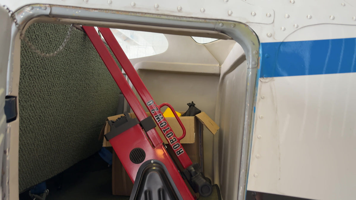 A Robotow 2.0 Pro frame folded, standing in an open baggage compartment.