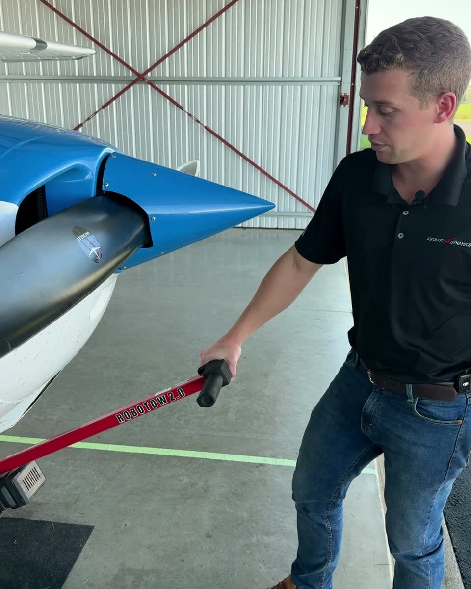 One person walking a Cessna 172 with a Robotow 2.0, both hands on the handle.