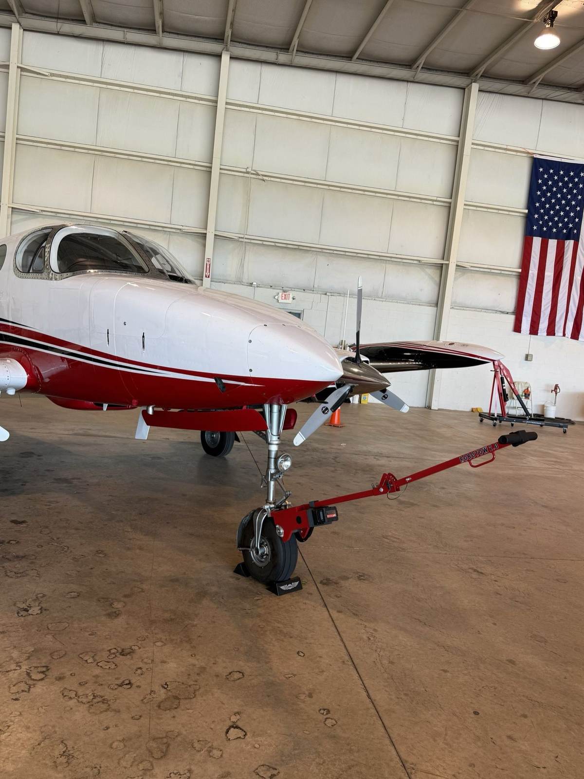 A Robotow on the nose gear of a Cessna 421 in a hangar.