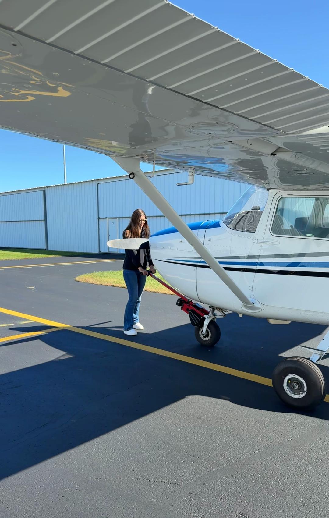 One person walking a Cessna 172 across the ramp with a Robotow 2.0 on its nose wheel, under the wing.