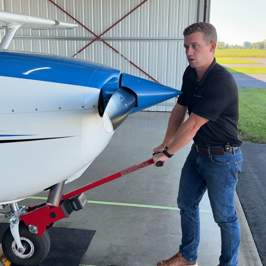Leaning on the Robotow 2.0 handle to move a Cessna 172 out of the hangar.