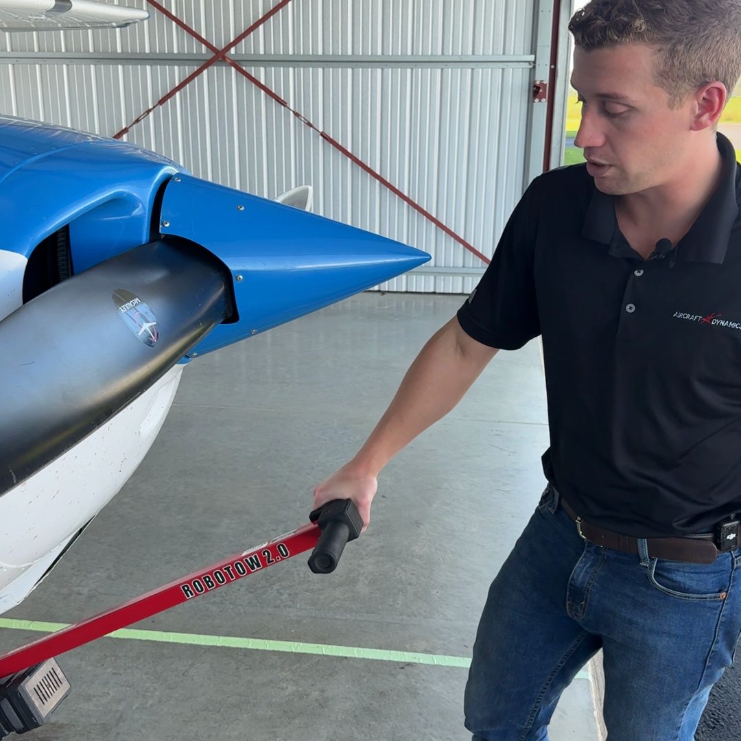 A hand on the Robotow 2.0 grip, steering a Cessna 172 nose wheel in the hangar.