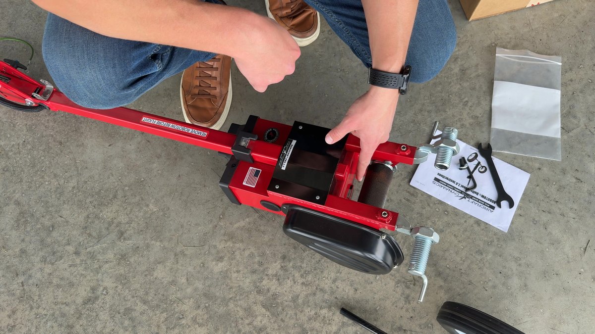 A Robotow 2.0 unit with its adapter hardware, wrenches and parts bag laid out on a hangar floor.